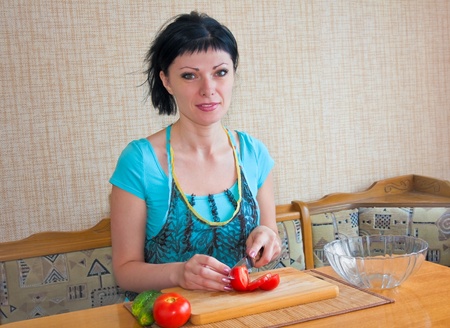 young woman in the kitchen cut the tomatoes and cucumbersの写真素材