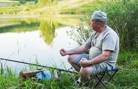 old fisherman sits on the shore of Lake tristeの写真素材