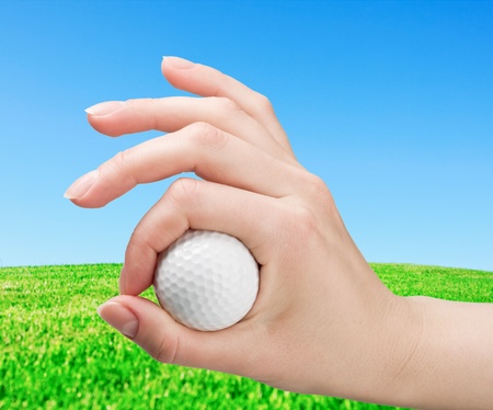 hand holds a ball for game in golf against a fieldの写真素材