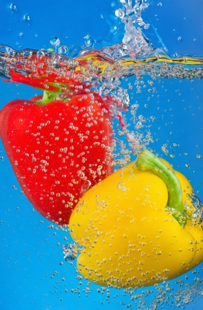 red and yellow pepper are dropped into waterの写真素材
