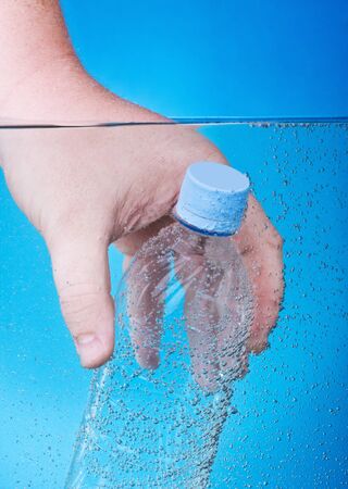 water bottle in his hand submerged in blue waterの写真素材