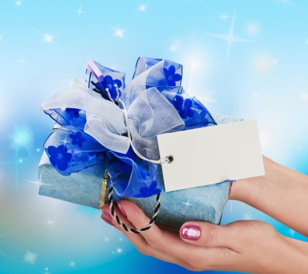 Blue gift in a female hand on the background of starsの写真素材