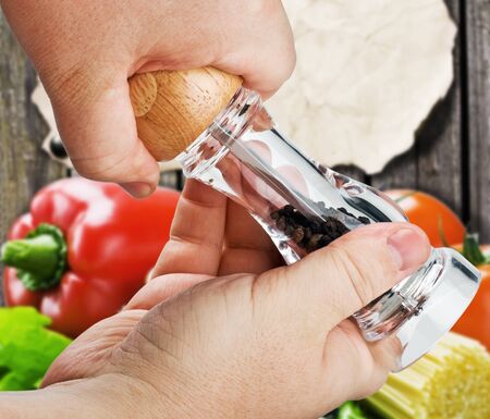 mill for spices in the hands isolated on a background of foodの写真素材