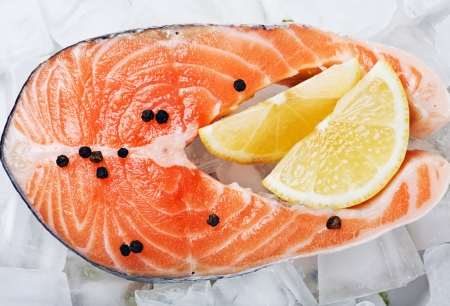 salmon steak with slices of lemon and black pepper on the ice の写真素材