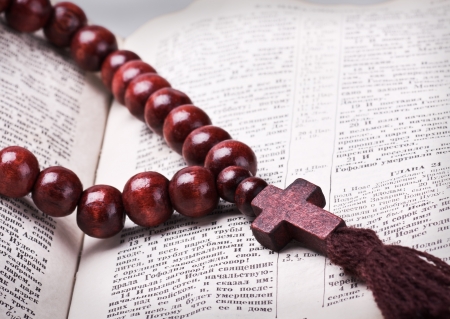 rosary with a wooden cross lying on open Bibleの写真素材