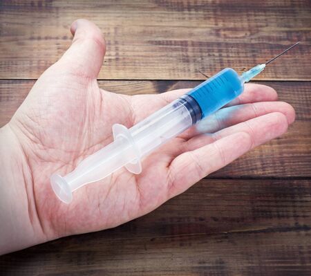 syringe with a blue drug or medicine in a handの写真素材