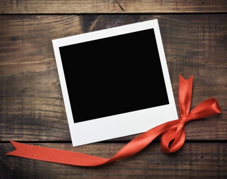 photo frame with a red bow on a wooden background