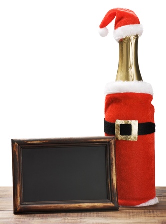 empty blackboard with wooden frame and a bottle of champagne in a Santa suitの写真素材