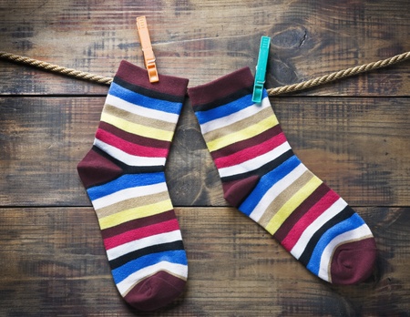 colorful socks hanging on clothespins against a wooden wallの写真素材