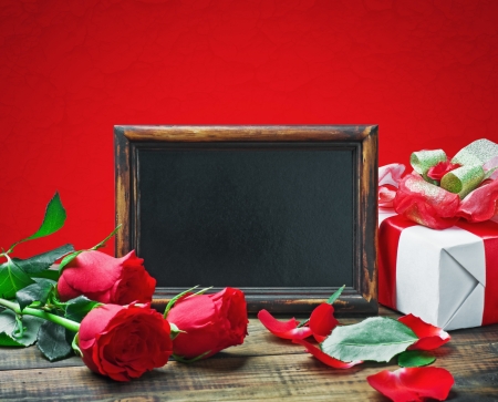 Red roses and gift for Valentine's Day or a birthday on a red backgroundの写真素材