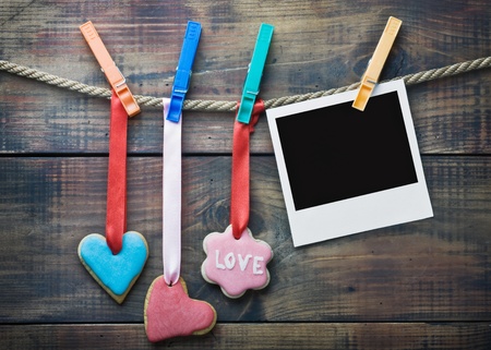 Valentine cookies and picture frame hanging on a rope on a wooden backgroundの写真素材