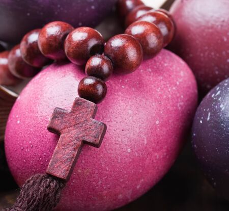 colorful painted Easter eggs on the background and wooden rosary