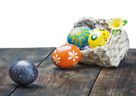 Painted Easter eggs in a basket on the table with space for textの写真素材