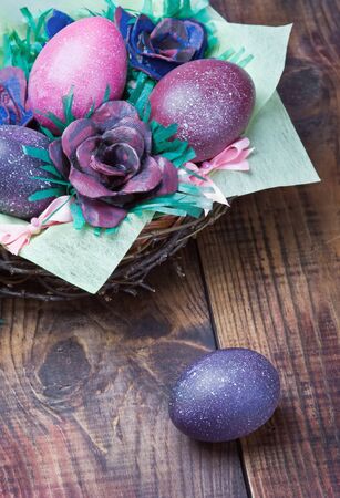Colorful easter eggs in brown a basket on a wooden table の写真素材