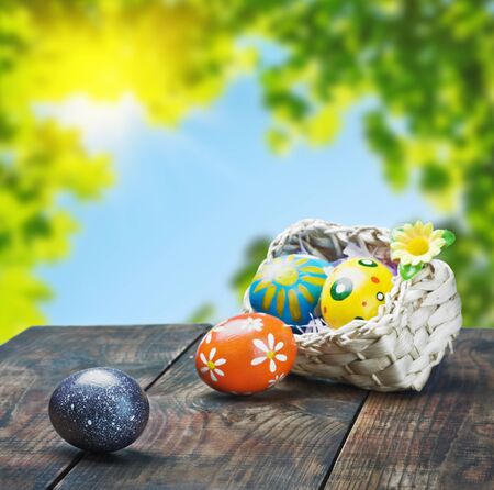 Painted Easter eggs in a basket on the table with space for textの写真素材