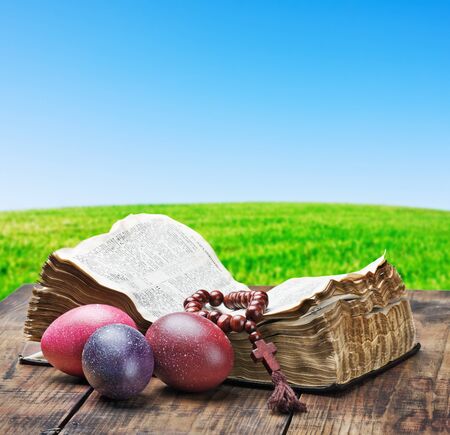 decorated with painted Easter eggs and an open bible wooden tableの写真素材