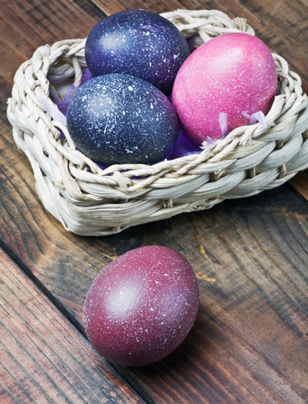 Colorful easter eggs in brown a basket on a wooden tableの写真素材