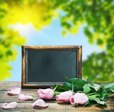 blackboard and pink roses on a background of natureの写真素材