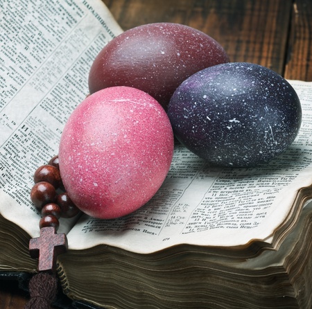 decorated with painted Easter eggs and an open bible wooden tableの写真素材
