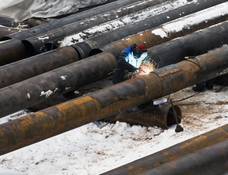 welder welds metal pipes in winterの写真素材