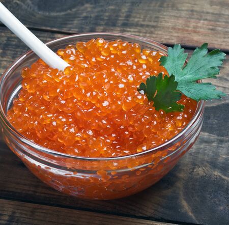 red caviar in a bowl on a wooden tableの写真素材