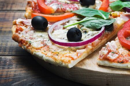 pizza with salami, olives and cheese cut into chunksの写真素材