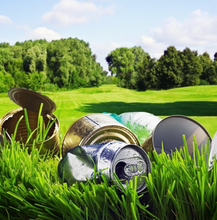 old aluminum and tin cans on a background of green fieldの写真素材