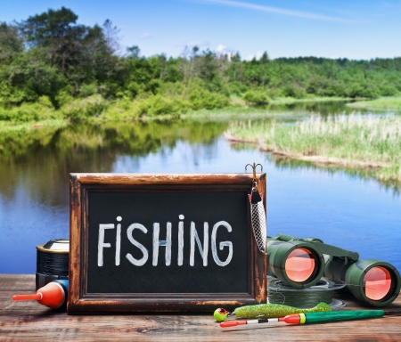 fishing tackle and a blackboard on a background of lakeの写真素材