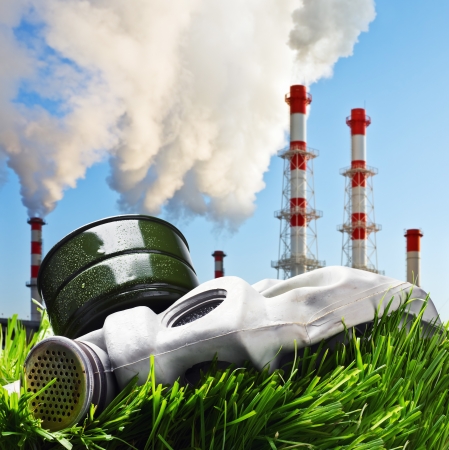 old gas mask on a green grass on a background of smoking chimneys polluting the planetの写真素材