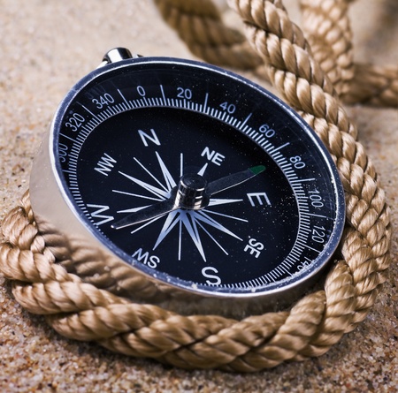 Compass with a rope coiled on the sea sandの写真素材