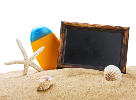 sunblock and a blackboard on the sea sand with shellsの写真素材