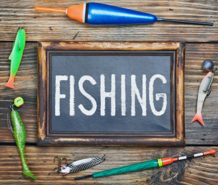 fishing gear and blackboard on wooden backgroundの写真素材
