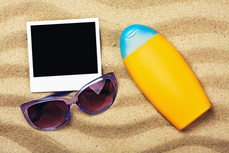 photo frame, sunblock and sunglasses on sandの写真素材