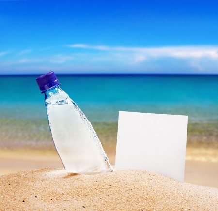paper for text and a bottle of water on the shore of the beachの写真素材