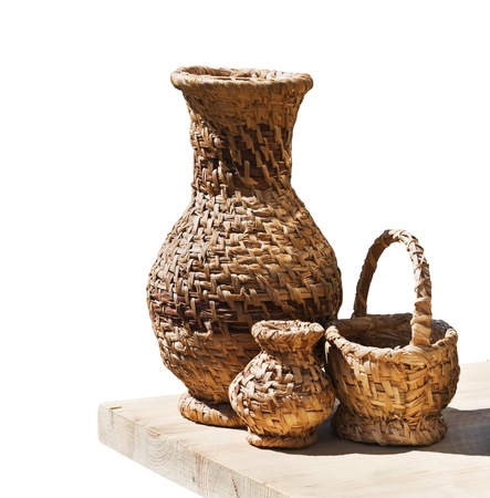 Wicker crockery on a wooden table isolated on white backgroundの写真素材