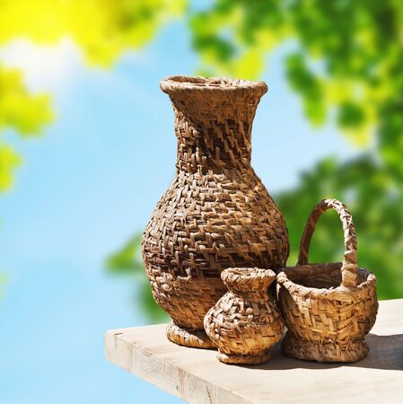 Wicker crockery on a wooden table on a background of natureの写真素材