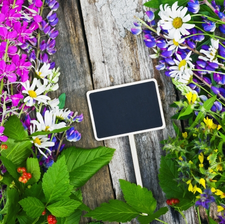 wild flowers and a black board for the text lie on a wooden tableの写真素材