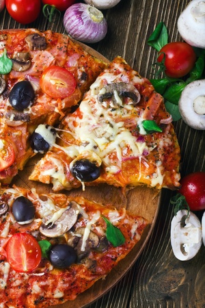 pizza with mushrooms and cheese and vegetables on a wooden tableの写真素材