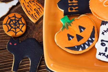 Halloween cookies on orange plate and wooden tableの写真素材