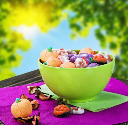 sweets and candies for the holiday halloween on a background of leaves and skyの写真素材