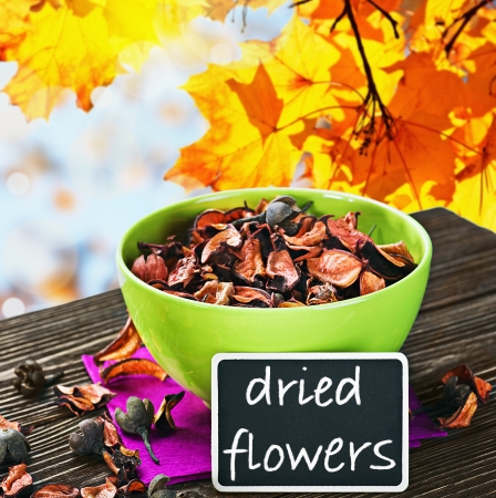 dried flowers and a plaque with the inscription on the background of autumn leavesの写真素材