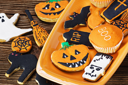 Halloween cookies on orange plate and wooden tableの写真素材