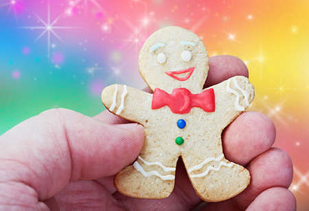 smiling gingerbread man in a hand on a colorの写真素材