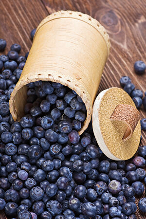 Blueberries in a basket is scattered on the wooden tableの写真素材