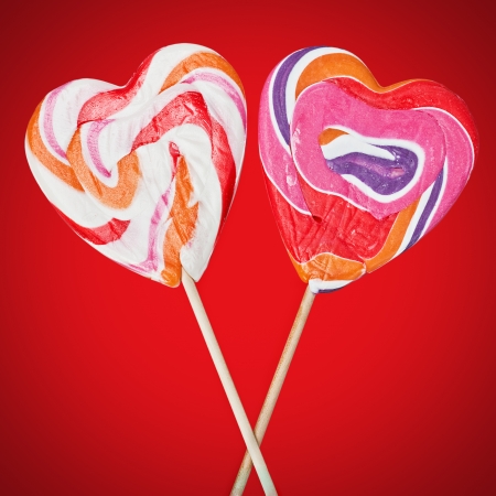 lollipops on sticks in the form of heart on a red backgroundの写真素材