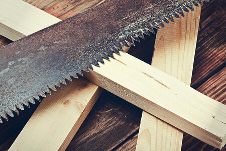 teeth of an old metal saws and sawn timber on the table. Focus on the teeth of the saw