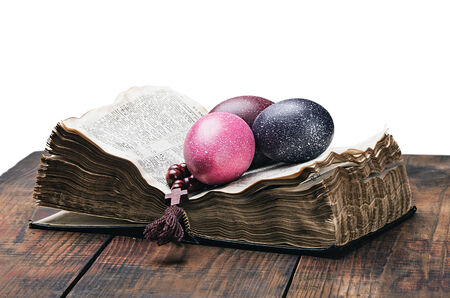 Easter egg and a rosary on an open Bible on a white backgroundの写真素材