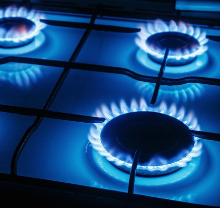 Blue flames of gas burning from a kitchen gas stove. Focus the front edge of the hotplateの写真素材