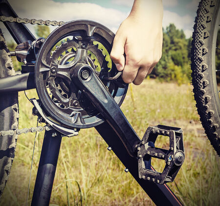 hand with key repairs bicycle against the sky. toned image