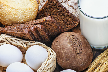 fresh bread and rolls with ears of wheat on the tableの写真素材